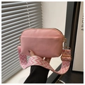 Close-up of pink crossbody bag with wide patterned shoulder strap and gold hardware - Pink