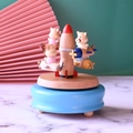 Macro detail of a wooden music box with small pigs on planes circling a central rocket - Pig Airplane Rocket Style / Blue
