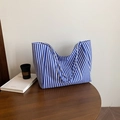 Blue and white striped canvas tote bag with front pocket and shoulder straps on a wooden table - Blue