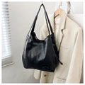 Detalle de bolso tote negro con diseño geométrico de retazos en cuero suave mate en ambiente moderno - Negro
