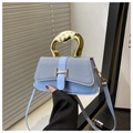 Detail of light blue crossbody bag with gold wavy handle and textured fabric flap - Blue