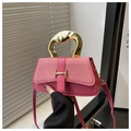 Detailed close-up of pink handbag featuring a gold H-shaped buckle and unique metal handle - Pink