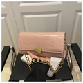 Close-up of pink faux crocodile skin texture and chunky gold chain strap on the handbag - Pink
