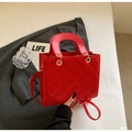 Détail du motif matelassé rouge avec ferrures métalliques dorées sur un sac à main femme - Bordeaux