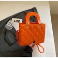 Close-up of the orange quilted diamond pattern and glossy PU leather on the handbag - Orange