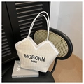 Detail van geweven strooien draagtas met witte lederen rand en zwart MOBORN PARIS logo - Wit