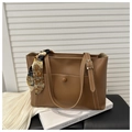 Detail of caramel tote bag with contrast stitching and decorative silk scarf on handle - Tan