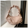 Detalle de bolso medialuna rosa con lazos y asa plisada junto a una ventana - Rosa