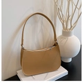 Close-up of khaki underarm bag with pebble leather texture on minimalist white background - Brown
