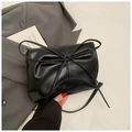Détail du sac en cuir PU noir avec grand nœud et plis texturés sur un fond de tissu doux - Noir