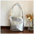 Close-up of metallic silver pleated tote bag featuring a decorative cream lace bow charm - Silver