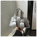 Macro detail of silver trapezoid handbag featuring wide handles and large metal buckles - Silver