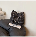 Detalle de un bolso tote floral con flores amarillas sobre tela plisada negra - Negro