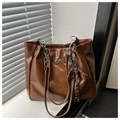 Detail einer braunen Lacktasche mit Silberschleife und dekorativen Taschenanhängern - Mit Anhänger / Braun