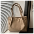 Detalle del bolso tote beige con textura de pata de gallo y asas trenzadas modernas - Caqui