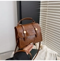 Detailopname van vintage bruine leren handtas met reliëfletters en gouden studs - Bruin