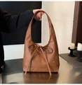 Detail of a brown tote bag featuring a leather bow and a silver heart-shaped metal logo - Brown