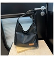 Detail shot of black leather hobo bag with a brown rectangular patch on marble surface - Black