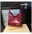 Detail of burgundy PU leather tote bag placed on a yellow art book in a minimalist setting - Burgundy