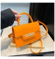 Close-up of bright orange leather handbag with premium gold chain link lock and top handle - Orange