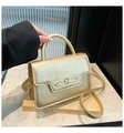 Detail of metallic gold handbag showing oval chain buckle and textured leather handle - Gold