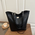 Vintage black crocodile embossed tote bag with gold metal plate on a wooden table - Black