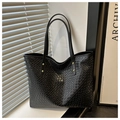 Detalle de bolso tote negro de cuero trenzado con remaches dorados y asa elegante - Negro
