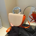 Orange crossbody bag with beige weave texture and fluid silver metal handle in mirror view - Orange