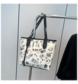 Detailed view of large tote bag featuring artistic graffiti prints and black PU leather straps - Black