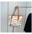 Detail of white tote bag with red graffiti bear prints and brown handles hanging on wall - Brown