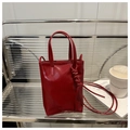 Detail of red leather mini tote bag with embossed fashion text and long shoulder strap - Red