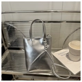 Detailed view of a silver metallic tote bag with decorative rope knots and brand lettering - Silver
