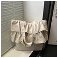 Detail of beige canvas tote bag with ruffled edges against a minimalist home background - White