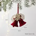 Cloche de Noël rouge floquée avec détails dorés scintillants sur branche enneigée - Pendentif Double Cloche avec Fleur Dorée