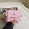 Close-up of a pink crossbody bag with V-shaped quilting and a white butterfly metal clasp - Pink