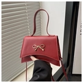 Detailaufnahme der roten Umhängetasche mit goldener Metallschleife und feinem Griff - Rot
