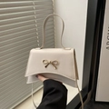 Cream white crossbody bag with golden bow hardware and curved base design - White