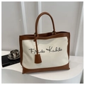 Dettaglio della borsa in tela con finiture in pelle marrone e scritta Frida Kahlo in posa - Bianco