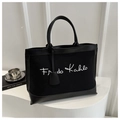 Dettaglio della grande borsa tote in tela nera con scritta Frida Kahlo e manici in pelle - Nero