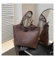 Detail of coffee brown leather tote bag with unique knotted handle and fashion label - Brown