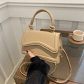 Borsa a tracolla beige con patta ondulata e manico annodato in un contesto di stile - Cachi