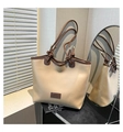 Close-up of contrast stitching, brown shoulder strap and fashion label on beige tote bag - Khaki