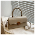 Detailed view of beige textured leather handbag with gold clasp on white knit fabric - Khaki