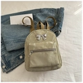 Detail of a mini beige backpack featuring a silver metal bow and unique marble texture - Green
