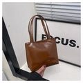 Détail d'un sac cabas en cuir verni marron brillant avec anses élégantes et logo - Marron