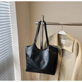 Detail of black oil-wax leather tote bag with slim shoulder strap on a hanger - Black