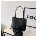 Détail d'un cabas en cuir verni noir brillant avec logo argenté et poignées fines - Noir