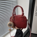 Red faux leather crossbody handbag with dual handles and a brown plush lion charm - With Pendant / Red