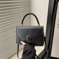 Minimalist black leather crossbody handbag with gold oval clasp and elegant top handle - Black
