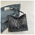 Nahaufnahme der Leopard-Print-Einkaufstasche auf weißem Stoff mit Jeansjacke und Buch - Schwarz